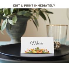 a place card sitting on top of a black plate next to a vase with greenery