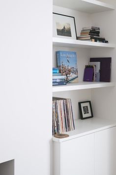 a white book shelf filled with lots of books next to a wall full of cds