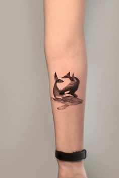 a woman's arm with a black and white whale tattoo on the left forearm