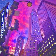 the sky is purple and pink as buildings stand in the city at night with lights on