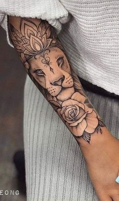 a woman's arm with a lion and roses tattoo on the left side of her arm