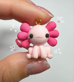 a tiny pink doll is sitting on someone's finger and holding it in her hand