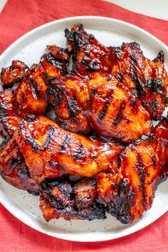 grilled chicken wings on a white plate with red table cloth and fork in the background