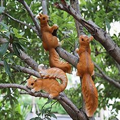 three squirrel figurines are hanging from a tree