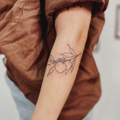 a woman's arm with a tattoo on it that has an olive branch and leaves