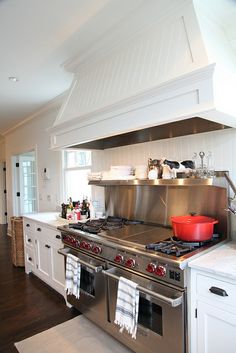 a kitchen with stainless steel appliances and white cabinetry, including an island countertop