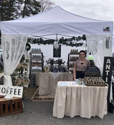 a woman standing in front of a tent selling coffee