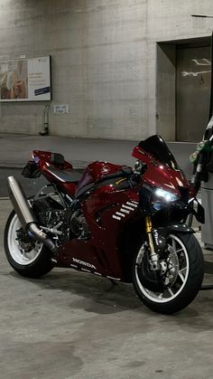 a red motorcycle is parked in front of a building with a man standing next to it