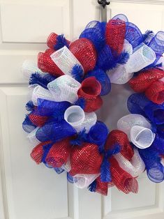 a red, white and blue mesh wreath hanging on a door