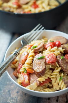 pasta with sausage and tomatoes in a white bowl