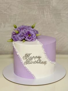 a purple and white birthday cake with flowers on top