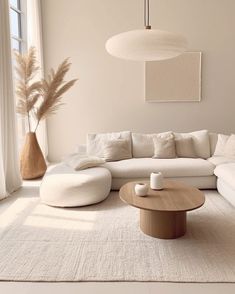 a living room with a large white couch and round coffee table in front of a window