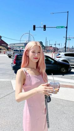 a woman with pink hair is holding a drink