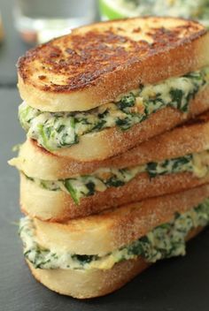 a stack of four grilled cheese sandwiches sitting on top of a black countertop