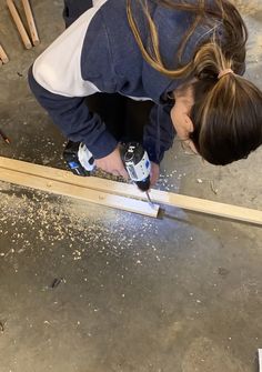 a woman is working on some wood with a drill and screwdriver in her hand