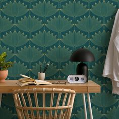 a table with a lamp, book and plant on it next to a wallpaper