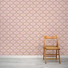 a wooden chair sitting in front of a wall with a geometric pattern on it's side