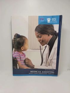 the medical assisting manual is open to show an image of a woman with a stethoscope