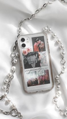 an iphone case with photos and pearls attached to it on a white sheeted surface