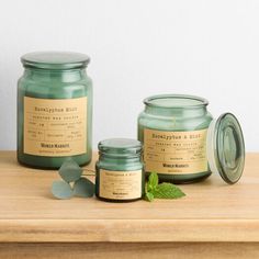 three jars of candles sitting on top of a wooden table