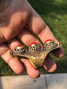 Beautiful vintage tribal saddle full finger ring Red gemstones or glass? Brass intricate carving Adjustable between sizes 9- 11. This is a gorgeous and very unique finger ring. There are three round cut cabochons and I am not sure what they are made of, they could be gemstone or they could be glass. The ring itself appears to be brass and someone could probably give it a good polishing if desired although I think it adds to the character the way it is. The ring Can fit anywhere from a size 9 thr Bohemian Toe Ring Jewelry For Ceremonial Occasions, Bohemian Toe Ring Jewelry For Ceremonies, Unique Jewelry With Intricate Design, Unique Metal Rings For Festivals, Unique Carved Ring Jewelry, Traditional Carved Rings For Ceremonial Occasions, Unique Ceremonial Ring Jewelry, Traditional Carved Ceremonial Rings, Vintage Festival Ring