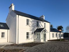 a large white house sitting on top of a gravel field