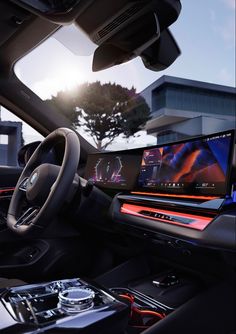 the inside of a car with an entertainment system and steering wheel, in front of a building