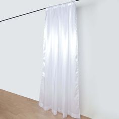 a white curtain hanging on a wall next to a wooden floor in an empty room