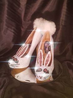 a pair of white shoes with bunny ears on them sitting on top of a plate