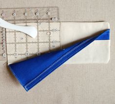 the ruler is next to a piece of cloth with a blue triangle on it and a white plastic spoon