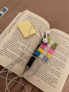 an open book with headphones on top of it next to a pair of earbuds