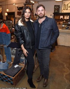 a man and woman standing next to each other in a room with clothes on display