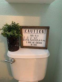 a toilet with a sign on the tank that says caution, this is a child's bathroom i have no control in here