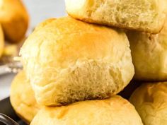 a pile of bread rolls sitting on top of a black plate next to oranges