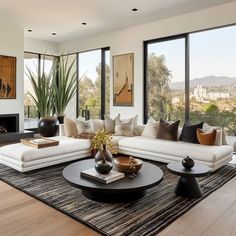 a living room filled with white furniture and lots of windows overlooking the cityscape