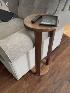 a remote control sitting on top of a wooden table next to a couch with a book