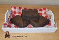 some brownies are in a white tray on a wooden table with a red and white checkered cloth