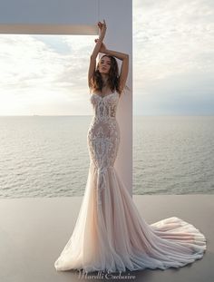 a woman in a wedding dress is posing by the water with her hands on her head