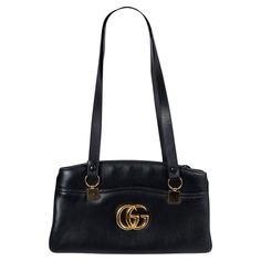 100% authentic Gucci Arli large tote in black calfskin featuring gold-tone hardware. The interior is divided in two compartment with zipper closure and lined in light pink grosgrain fabric with one zipper pocket against the back. The design features a large gold-tone GG on the front, one open pocket on the front and on the back, and adjustable shoulder-straps. Has been carried and shows soft scratches to the front and back. Overall in excellent condition. Comes with dust bag. 2019 Resort Measure Gucci Black Bag, Gucci Leather, Gucci Black, Black Bag, Handle Bag, Large Tote, Fashion Handbags, Shoulder Straps, Top Handle