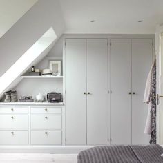 an attic bedroom with white cabinets and drawers