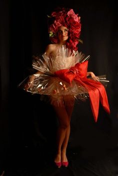 a woman in a red dress with flowers on her head and hands behind her back