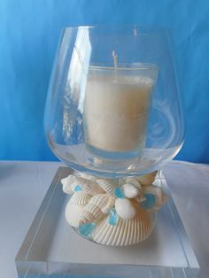 a candle sitting in a glass bowl on top of a table with shells and seashells