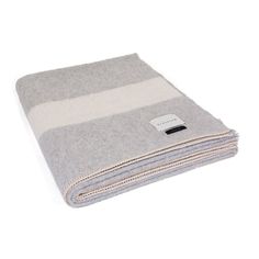 grey and white blanket folded on top of each other with a black tag in the middle