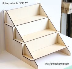 three cardboard display shelves sitting on top of a white table next to a wall with text overlay that says 3 tier portable display