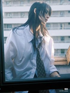 a woman with long hair wearing a white shirt and tie standing in front of a window