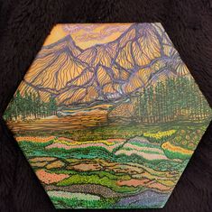 a painting on a piece of wood with mountains in the background