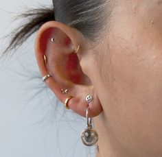 a close up of a person wearing ear piercings and an earring on their left side