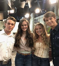 three young people standing next to each other in front of a tv studio light fixture