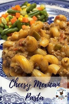 a blue and white plate topped with pasta and veggies