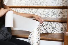 a woman is sitting on the stairs holding a roll of paper